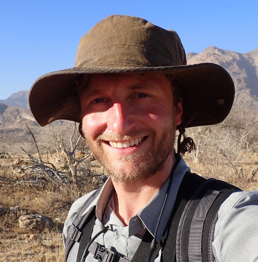 photo of a smiling white man wearing a broad brimmed hat